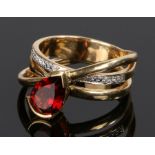 18 carat gold garnet and diamond set ring, with a cross over shank set with a pear cut garnet and