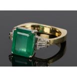 18 carat gold emerald and diamond set ring, the central emerald at approximately flanked by two