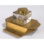 Art Deco brass and glass inkwell, the hinged brass lid above a clear glass body and brass base