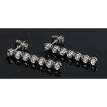 Pair of 18 carat white gold diamond set earrings, the drops with seven round cut diamonds, 26mm long