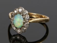 18 carat gold opal and diamond ring, the central oval opal surrounded by a band of diamonds, ring