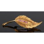 18 carat gold and ruby set brooch, in the form of a leaf with a row of rubies, 6.6 grams, 57mm