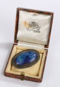 Ruskin brooch, the oval blue panel housed in a pierced white metal mount, 43mm x 27.5mm