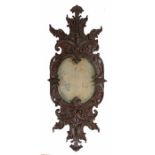 18th Century German wall mirror, the oval mercury plate within the oak frame having C scrolls and