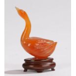 Chinese hardstone carving, of a swan in pale orange, 6cm high, together with the stand
