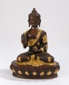 Bronze Buddha, legs crossed with hand raised and gilt heightened decoration, 26cm high