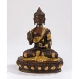 Bronze Buddha, legs crossed with hand raised and gilt heightened decoration, 26cm high