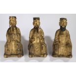 Set of three Chinese gilded altar figures, of immortals, seated position with flowing robes, 36cm