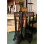 Pair of ebonised oriental candle stands, with adjustable centres, raised on scroll carved feet,