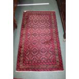 Middle Eastern rug, the dark red ground with geometric motifs in a floral border, with a label to