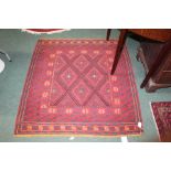 Middle Eastern style rug, the red ground with a blue and yellow geometric pattern surrounded by a