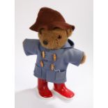 Paddington Bear teddy bear, wearing a burgundy hat, blue duffle coat and red wellington boots,