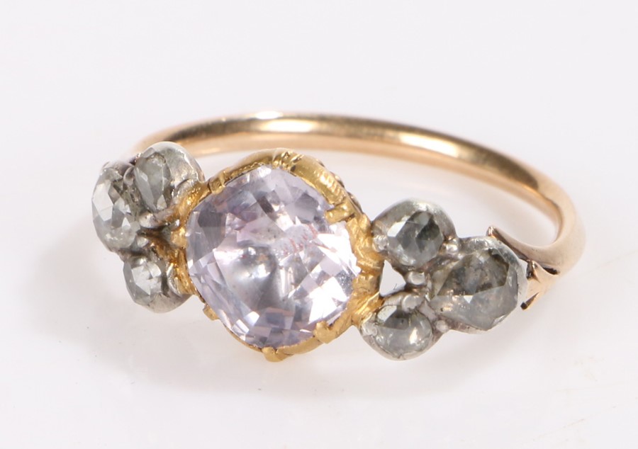 Gold coloured metal ring, the central purple paste flanked by three rose cut diamonds to each