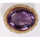 Amethyst brooch/ pendant, the central oval amethyst surrounded by a band of garnets and white