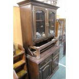 Dark stained dresser with two glazed cupboards above an open recess, the base with two drawers and