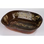 19th Century slipware pottery baking dish, with wriggle slipware design and a brown glaze ground,