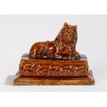 19th Century treacle glaze lion, mounted on a plinth base, 15.5cm long
