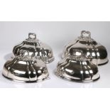 Graduated set of four silver plated meat domes, with pierced rococo scroll and foliate handles above