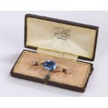 Sapphire and diamond set brooch, the oval light blue sapphire at 5.76 carats flanked by two round