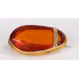 9 carat gold amber brooch, with an amber pebble mounted in gold, 36mm long