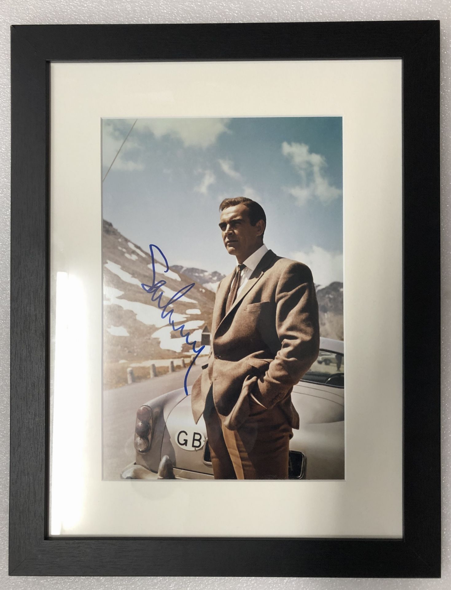 A signed photograph of Sean Connery as James Bond with the 'Goldfinger' Aston Martin DB5,