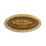 An oval plaque celebrating Duesenberg's 1921 French Grand Prix victory,