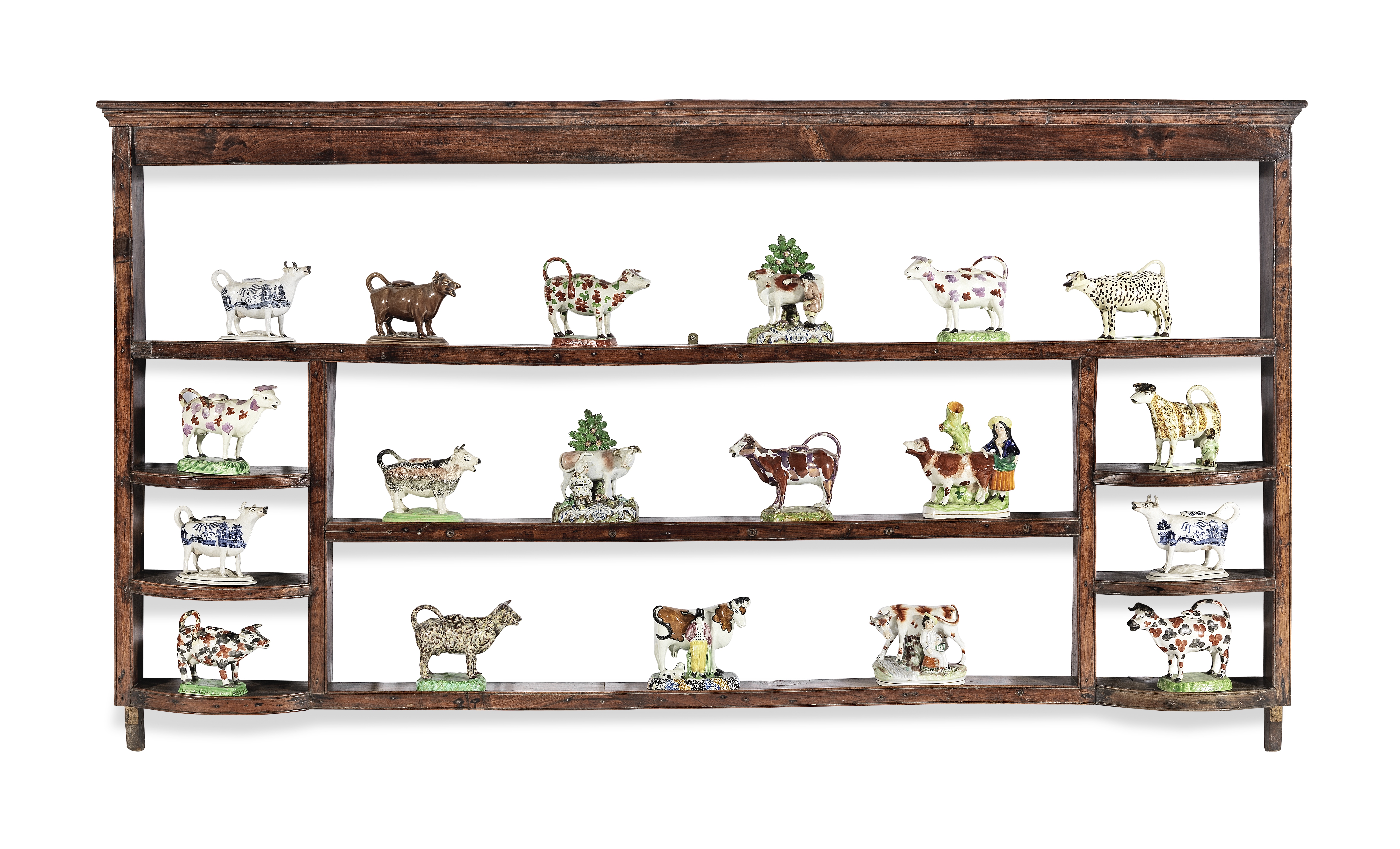 A large collection of pottery cow creamers together with a plate rack