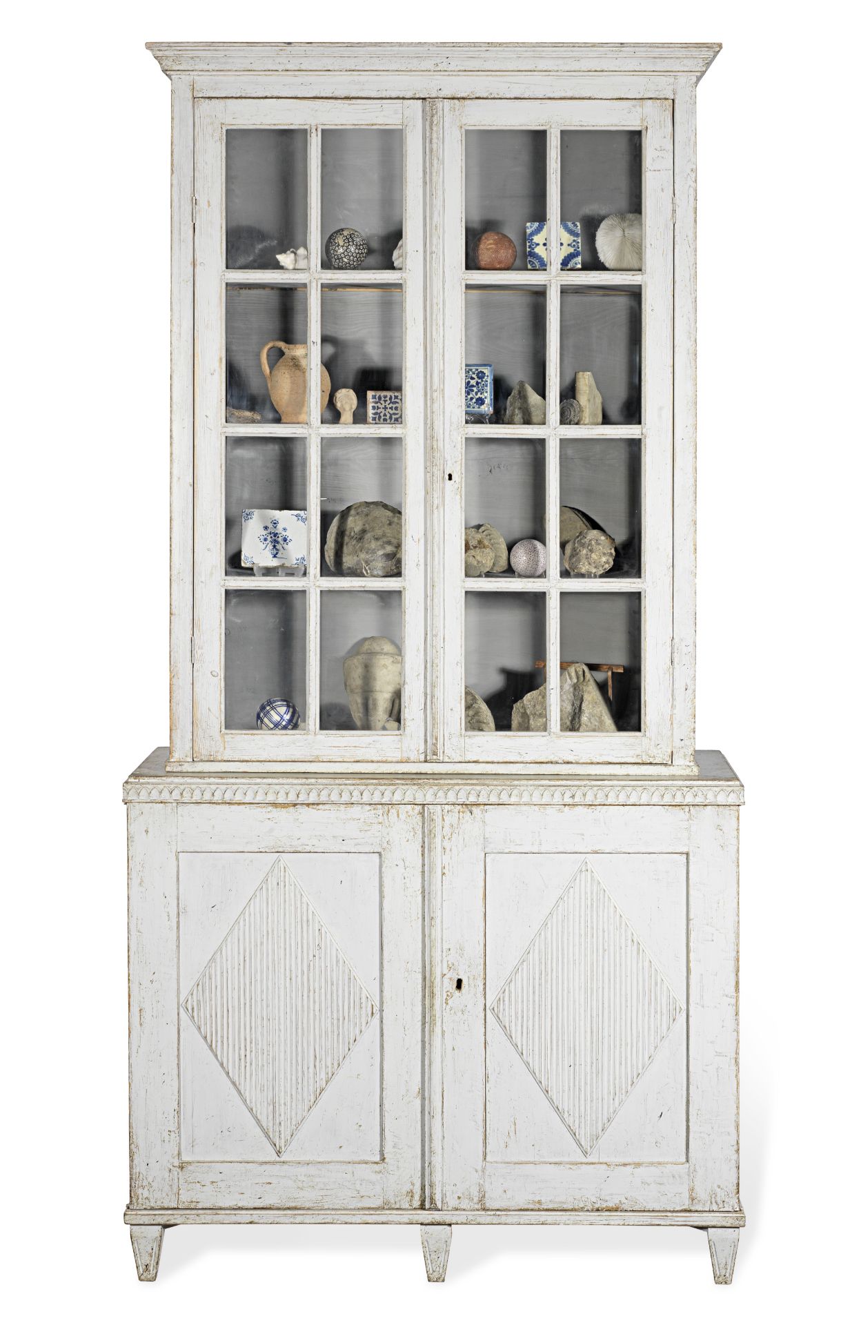 A Gustavian style painted bookcase enclosing a collection of natural history specimens and potter...