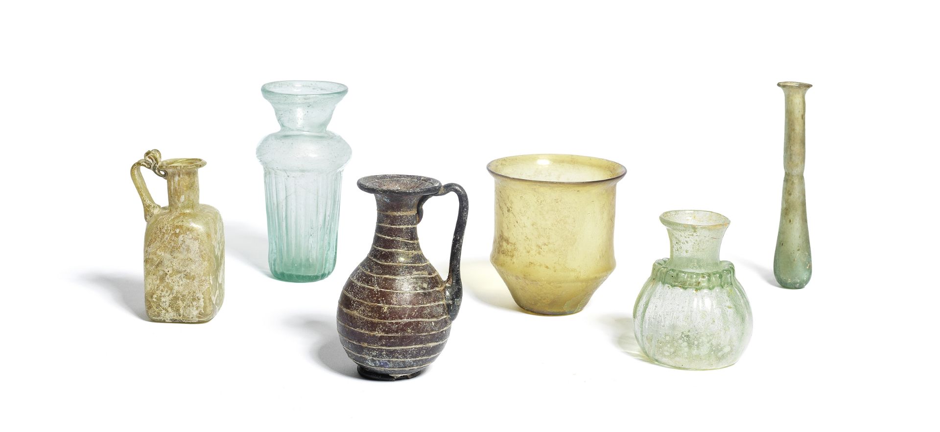 Four Roman glass vessels together with an aubergine glass bottle and a green glass bottle, 6