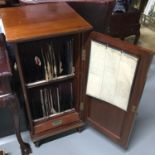 An antique Mahogany record cabinet produced by Disque Cabinets 1910. Contains old records. Cabinet