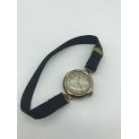 A Vintage 9ct gold watch in a working condition. Has a black material strap.