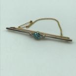 A Gold unmarked bar brooch set with a large sky blue topaz with two large side Diamonds. Weighs 5.