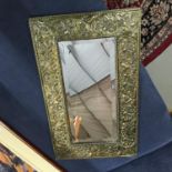 An Arts and crafts brass ornate bevel edge wall mirror. Measures 57X34CM