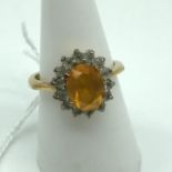 A 14ct gold ladies ring set with a large orange cut stone surrounded by clear stones. Ring size P