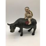 An Antique Chinese porcelain nude boy figure riding on top of an OX/ Buffalo. Highly detailed paited