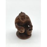A Japanese hand carved netsuke figure of an elderly gentleman carrying a lantern and a mask.