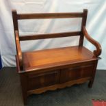 A hardwood reproduction hall way monk settle. Designed with curved arm rests. Pedestal legs and lift