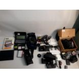 A large collection of cameras and equipment to include battery chargers, manuals and film camera.