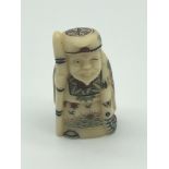 A Japanese hand carved netsuke figure of a Scholar, detailed with ornate gown and signed to the base