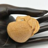 A Japanese hand carved tagua nut Netsuke. Designed into a piece of fruit with a small insect