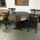 A vintage dark wood extending dining table together with two chairs and two carvers. Table