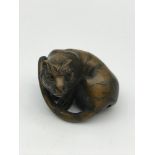 A Japanese hand carved netsuke figure of a Tiger. Detailed with black bead eyes and signed by the