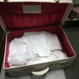 A Vintage travel case containing a collection of vintage table covers and linen