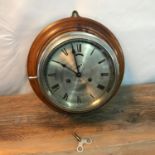 Antique Bulkhead wall clock, Set against a mahogany style wood. Comes with key. Runs for a short