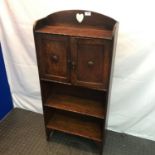 An narrow arts and crafts oak bookcase unit. Designed with two doors and three shelves. Arched top