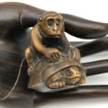 A Japanese hand carved netsuke figure of a monkey sat upon a turtle. Both detailed with black bead