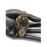 A Japanese hand carved netsuke figure of an elderly gentleman serving drinks from a barrel. Signed
