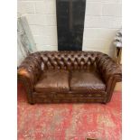 A Chesterfield Rustic brown leather two seat sofa.