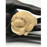 A Japanese hand carved tagua nut netsuke figure of a dog and basket. No signature.