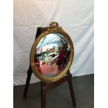 A Victorian/ Edwardian convex mirror designed with moulded wreath and foliage gilt frame. Measures